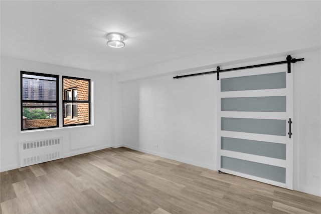 3184 Grand Unit 6D, Bronx, NY 10458 - empty room featuring radiator heating unit, a barn door, and wood finished floors