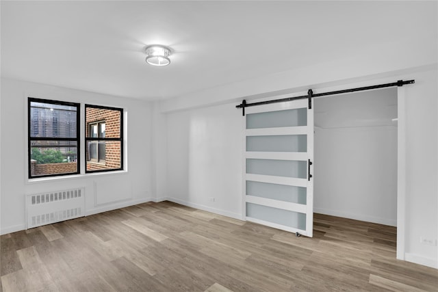 3184 Grand Unit 6D, Bronx, NY 10458 - unfurnished bedroom featuring radiator, a barn door, wood finished floors, and a closet