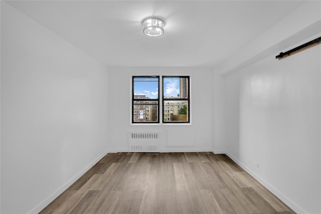 3184 Grand Unit 6D, Bronx, NY 10458 - unfurnished room featuring radiator, wood finished floors, and a barn door