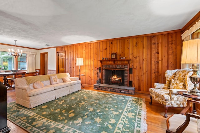27 E Woods Dr, Cold Spring Harbor, NY 11724 - living room with a chandelier, crown molding, a brick fireplace, wooden walls, and wood finished floors