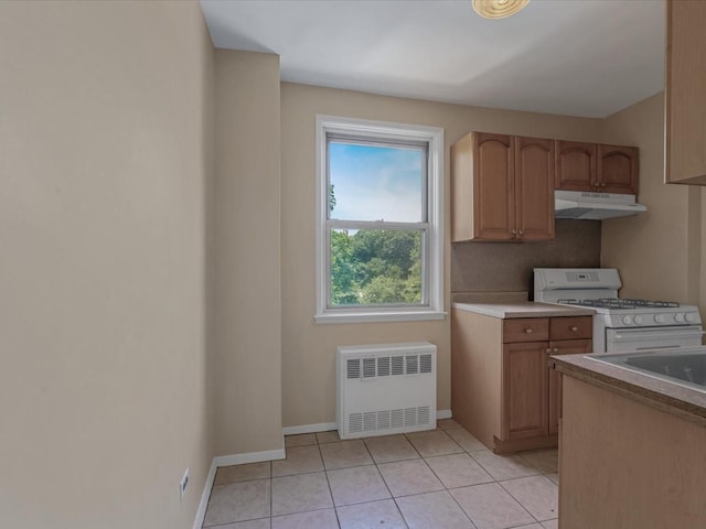 5500 Fieldstone Unit 4Ii, Bronx, NY 10471 - kitchen featuring under cabinet range hood, white gas range oven, radiator, light tile patterned flooring, and light countertops