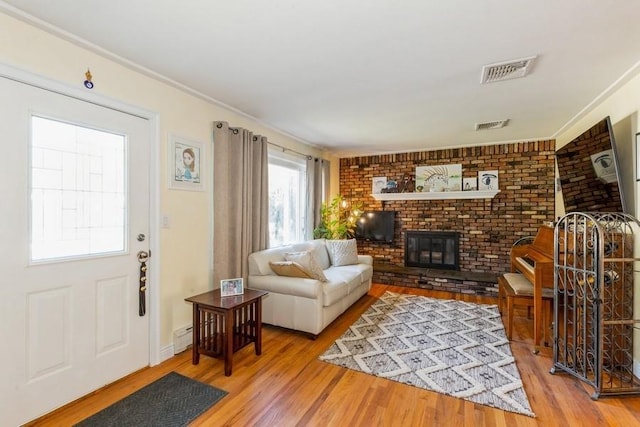 118 Pine Neck Ave, East Patchogue, NY 11772 - living room with wood finished floors, a fireplace, crown molding, and a baseboard radiator