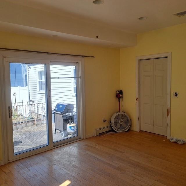 118 Pine Neck Ave, East Patchogue, NY 11772 - empty room with light wood finished floors and baseboard heating