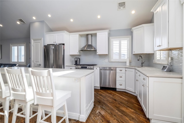 87 Arizona Ave, Long Beach, NY 11561 - kitchen featuring appliances with stainless steel finishes, wall chimney range hood, vaulted ceiling, white cabinets, and recessed lighting