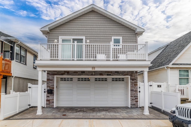 87 Arizona Ave, Long Beach, NY 11561 - view of front of property with a balcony, stone siding, an attached garage, driveway, and a gate