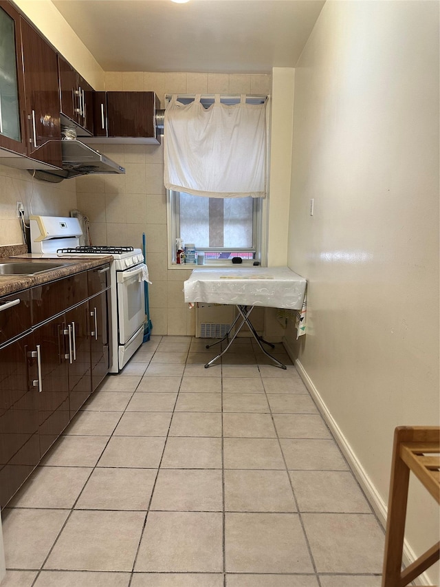27-04 Parsons Blvd Unit 2G, Flushing, NY 11354 - kitchen with white gas range oven, light tile patterned floors, dark brown cabinets, and glass insert cabinets