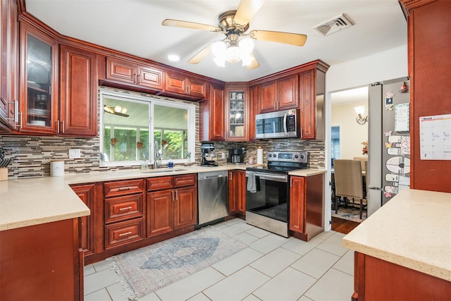 63 Lake Walton Rd, Wappingers Falls, NY 12590 - kitchen featuring stainless steel appliances, reddish brown cabinets, backsplash, a ceiling fan, and glass insert cabinets