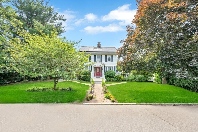118 Grant Ave, Albertson, NY 11507 - view of front of property featuring solar panels, a front lawn, and a chimney