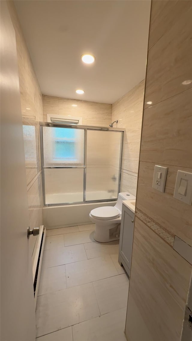 232-04 88th Ave, Queens Village, NY 11427 - full bathroom featuring bath / shower combo with glass door, vanity, a baseboard heating unit, tile patterned flooring, and tile walls