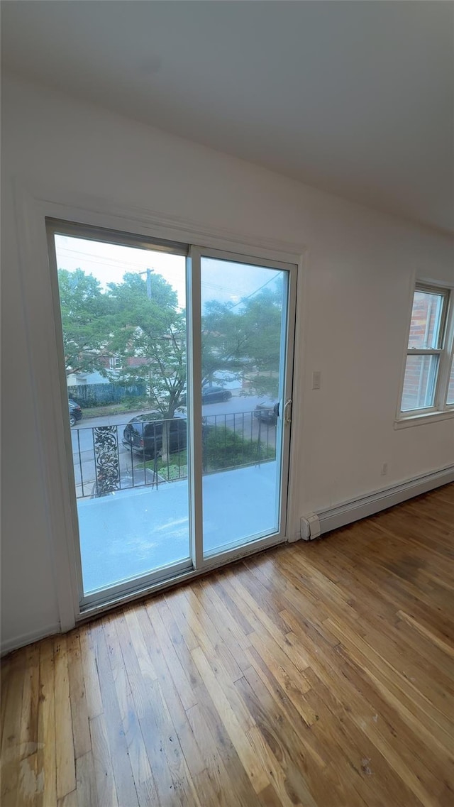 232-04 88th Ave, Queens Village, NY 11427 - spare room featuring a baseboard heating unit, hardwood / wood-style floors, and plenty of natural light