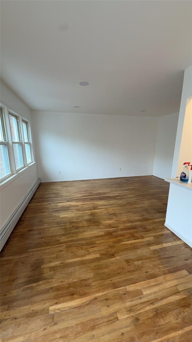 232-04 88th Ave, Queens Village, NY 11427 - empty room with wood finished floors and a baseboard heating unit