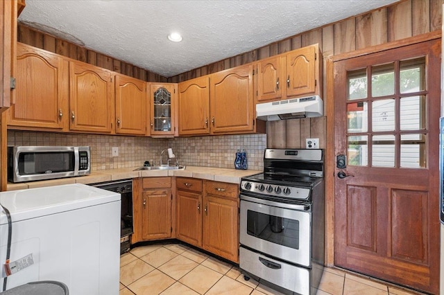 2354 7th St, East Meadow, NY 11554 - kitchen featuring appliances with stainless steel finishes, under cabinet range hood, light tile patterned floors, decorative backsplash, and a textured ceiling