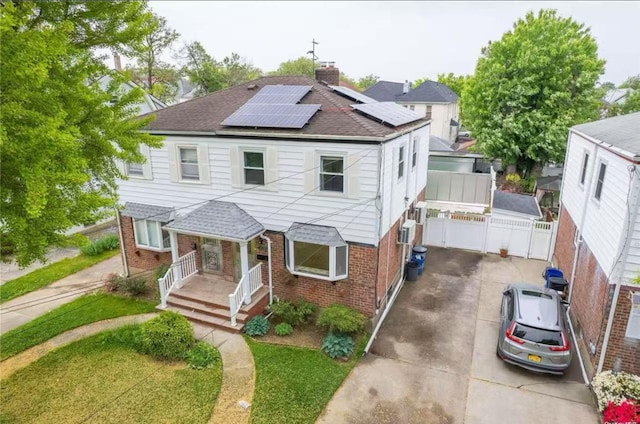 40-02 202nd St, Bayside, NY 11361 - view of front of home featuring brick siding, roof with shingles, roof mounted solar panels, a chimney, and a porch