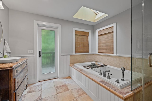 41 River Rd, Nyack, NY 10960 - full bathroom with a skylight, vanity, a garden tub, stone finish floors, and wainscoting