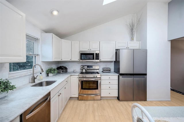 2508 Centre Ave, Bellmore, NY 11710 - kitchen featuring appliances with stainless steel finishes, decorative backsplash, white cabinetry, lofted ceiling, and light wood-style floors