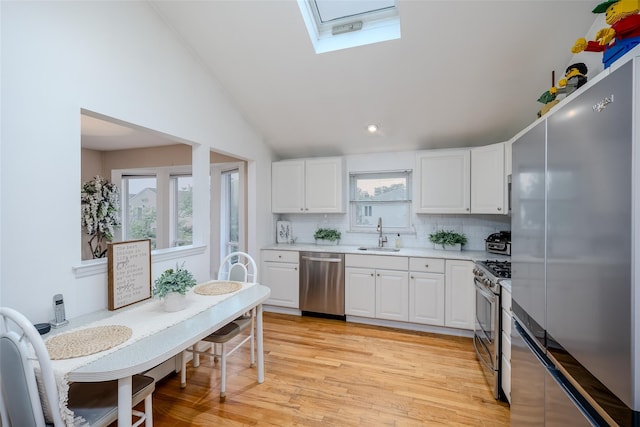 2508 Centre Ave, Bellmore, NY 11710 - kitchen with stainless steel appliances, a skylight, tasteful backsplash, white cabinetry, and light wood-type flooring