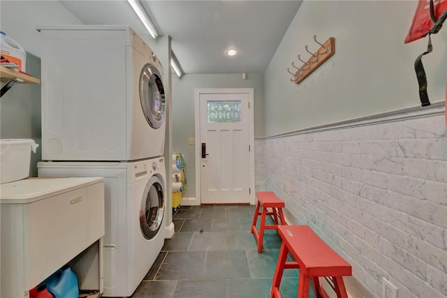 84 Highview Ave, Nanuet, NY 10954 - laundry area with stacked washer / drying machine, dark tile patterned floors, a wainscoted wall, and brick wall