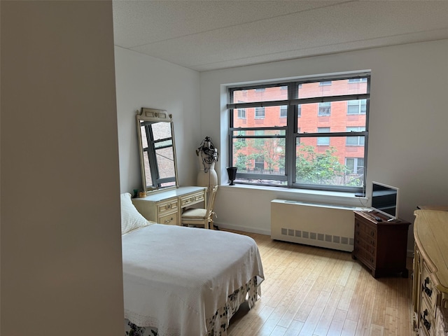 837 Washington Ave Unit 3A, Bronx, NY 10451 - bedroom featuring radiator heating unit, multiple windows, and light wood-type flooring