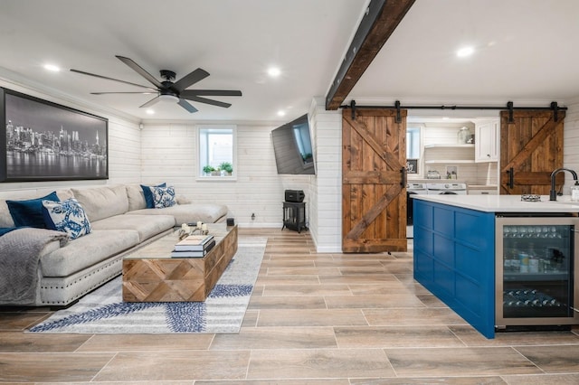35 Irenhyl Ave, Port Chester, NY 10573 - living room with wine cooler, a barn door, a ceiling fan, light wood-style flooring, and crown molding