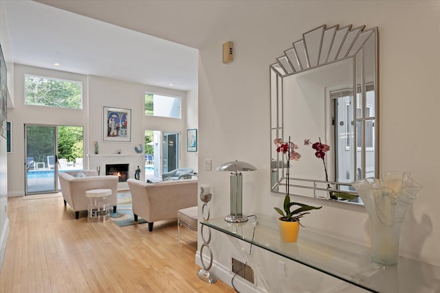 41 Park Cir, Quogue, NY 11959 - living room with a warm lit fireplace, wood-type flooring, recessed lighting, and a towering ceiling