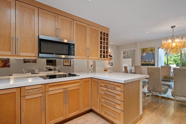 41 Park Cir, Quogue, NY 11959 - kitchen featuring stainless steel microwave, a peninsula, a chandelier, light wood-style flooring, and light countertops