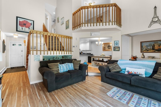 5 Rose Ests Unit 2, Walden, NY 12586 - living area with a towering ceiling, a chandelier, wood finished floors, stairs, and a baseboard heating unit