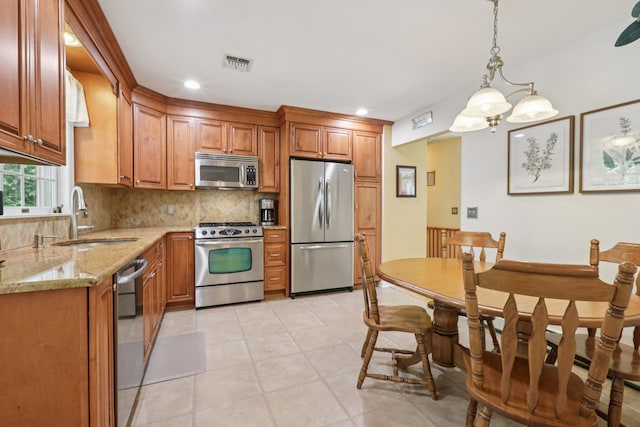 3 Hoyt Ct, Stony Point, NY 10980 - kitchen with appliances with stainless steel finishes, decorative backsplash, brown cabinetry, light stone counters, and pendant lighting
