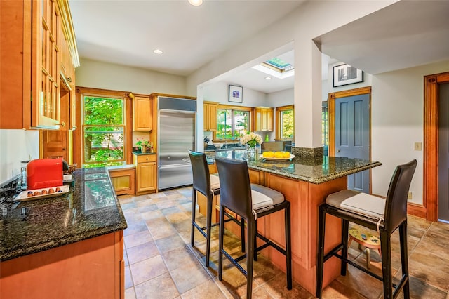 33 Ridge Rd, Ardsley, NY 10502 - kitchen featuring built in refrigerator, healthy amount of natural light, a breakfast bar, dark stone counters, and recessed lighting