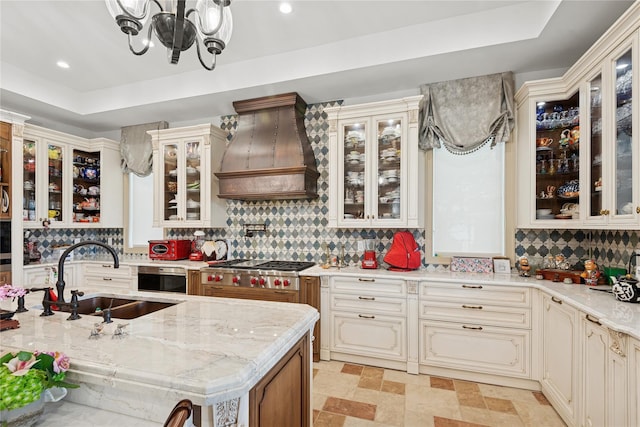 1190 Harbor Rd, Hewlett Harbor, NY 11557 - kitchen with custom exhaust hood, a tray ceiling, tasteful backsplash, a chandelier, and stainless steel gas stovetop