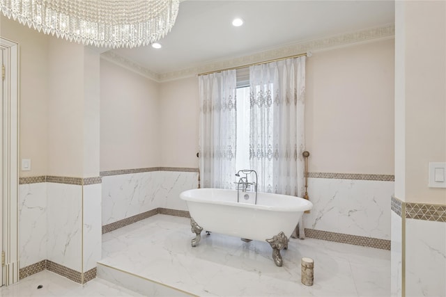 1190 Harbor Rd, Hewlett Harbor, NY 11557 - bathroom featuring a wainscoted wall, marble tiled flooring, tile walls, a soaking tub, and a chandelier