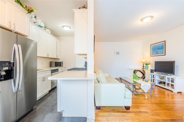 6109 39th Ave Unit J3, Woodside, NY 11377 - kitchen with stainless steel appliances, white cabinetry, light countertops, and a peninsula