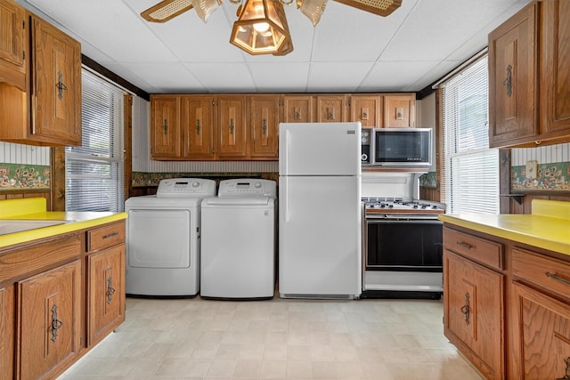 16 King St, Port Jervis, NY 12771 - kitchen with white appliances, washing machine and clothes dryer, ceiling fan, brown cabinetry, and light countertops
