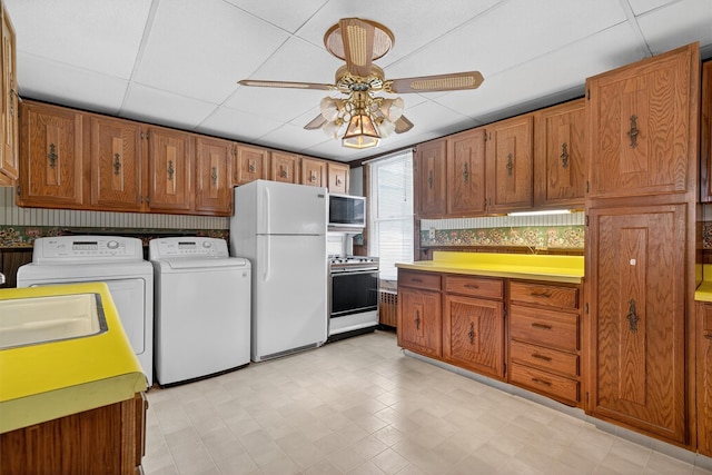 16 King St, Port Jervis, NY 12771 - kitchen featuring freestanding refrigerator, stove, washing machine and dryer, ceiling fan, and brown cabinetry