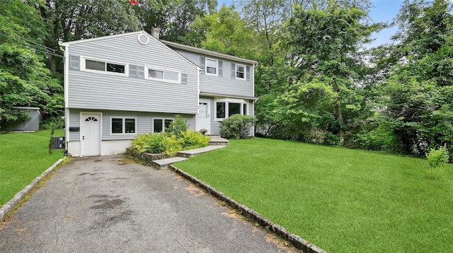 7 Kings Ln, Montrose, NY 10548 - view of front facade featuring a chimney, a front yard, asphalt driveway, and view of wooded area