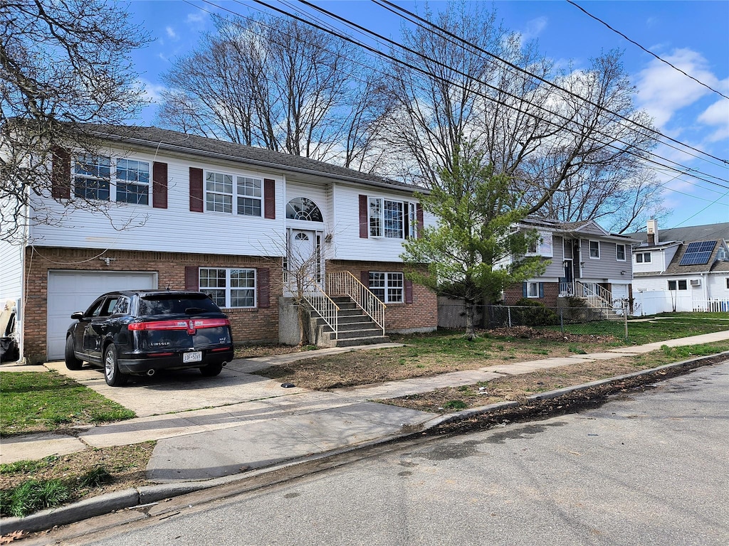 1056 E Arthur St, Uniondale, NY 11553 - bi-level home with an attached garage, brick siding, and concrete driveway