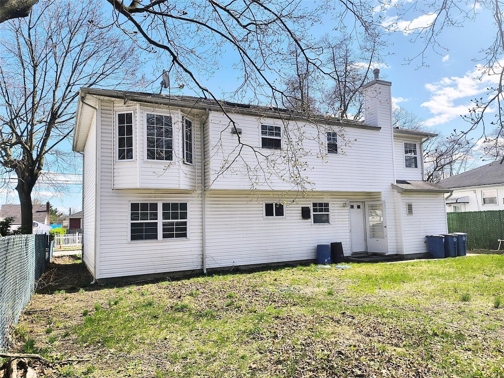 1056 E Arthur St, Uniondale, NY 11553 - back of property with a chimney and a fenced backyard