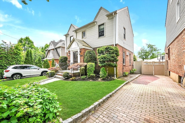 33-50 210th St, Bayside, NY 11361 - view of front of property featuring brick siding, a gate, a front yard, and driveway