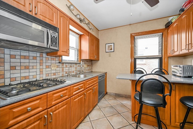33-50 210th St, Bayside, NY 11361 - kitchen featuring stainless steel appliances, decorative backsplash, a kitchen bar, and a ceiling fan