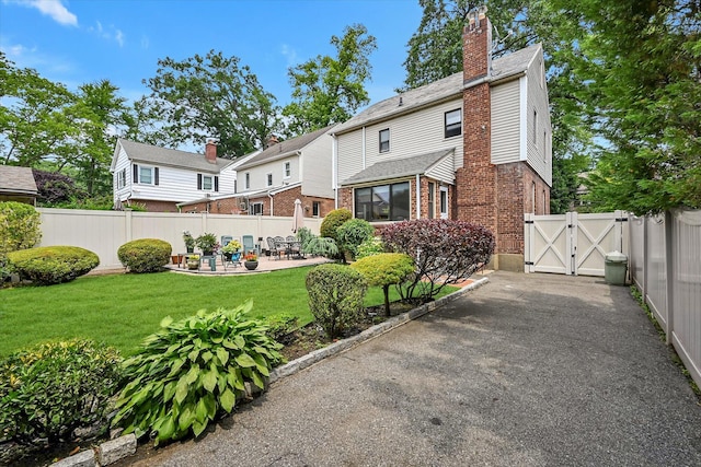 33-50 210th St, Bayside, NY 11361 - rear view of house featuring a gate, brick siding, a patio, and a chimney