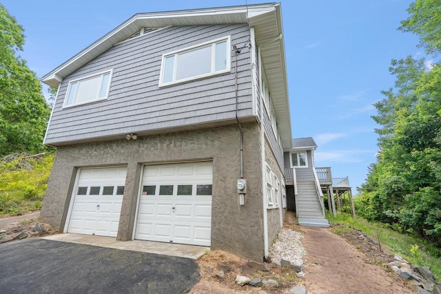542 Montauk Hwy, Southampton, NY 11968 - view of home's exterior with an attached garage, stucco siding, driveway, and stairs