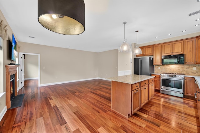 84 Jasmine Dr, Middletown, NY 10940 - kitchen featuring stainless steel range, freestanding refrigerator, black microwave, brown cabinets, and tasteful backsplash