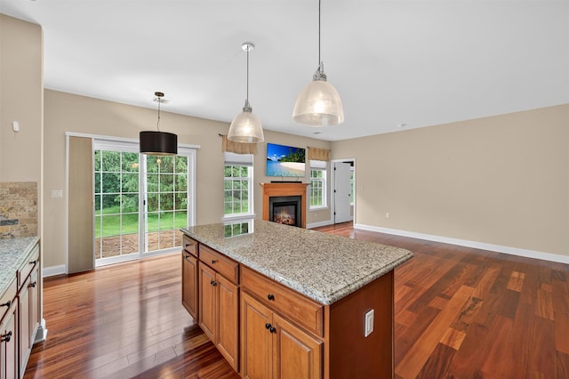 84 Jasmine Dr, Middletown, NY 10940 - kitchen with dark wood-style floors, light stone counters, a glass covered fireplace, open floor plan, and a kitchen island