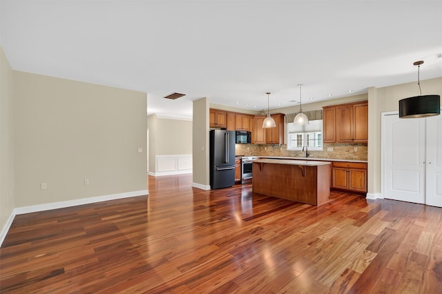 84 Jasmine Dr, Middletown, NY 10940 - kitchen featuring freestanding refrigerator, stainless steel stove, black microwave, brown cabinetry, and a kitchen bar