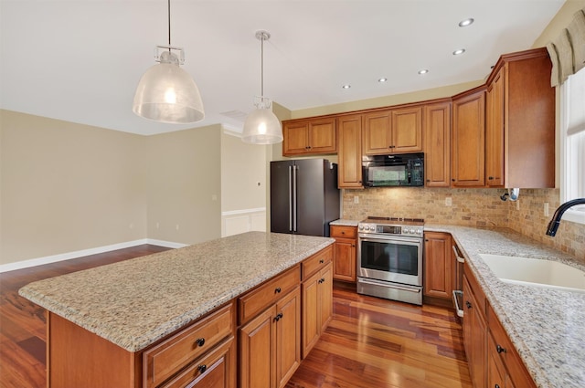 84 Jasmine Dr, Middletown, NY 10940 - kitchen featuring stainless steel appliances, brown cabinetry, decorative backsplash, light stone counters, and dark wood-style flooring