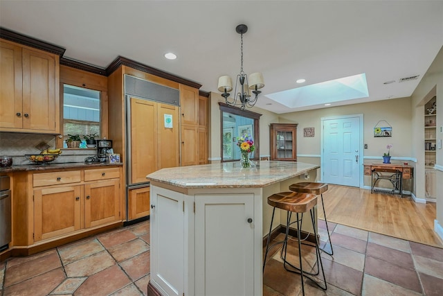 18 Huyler Ct, Setauket, NY 11733 - kitchen featuring paneled built in refrigerator, a skylight, a breakfast bar area, a chandelier, and light stone counters