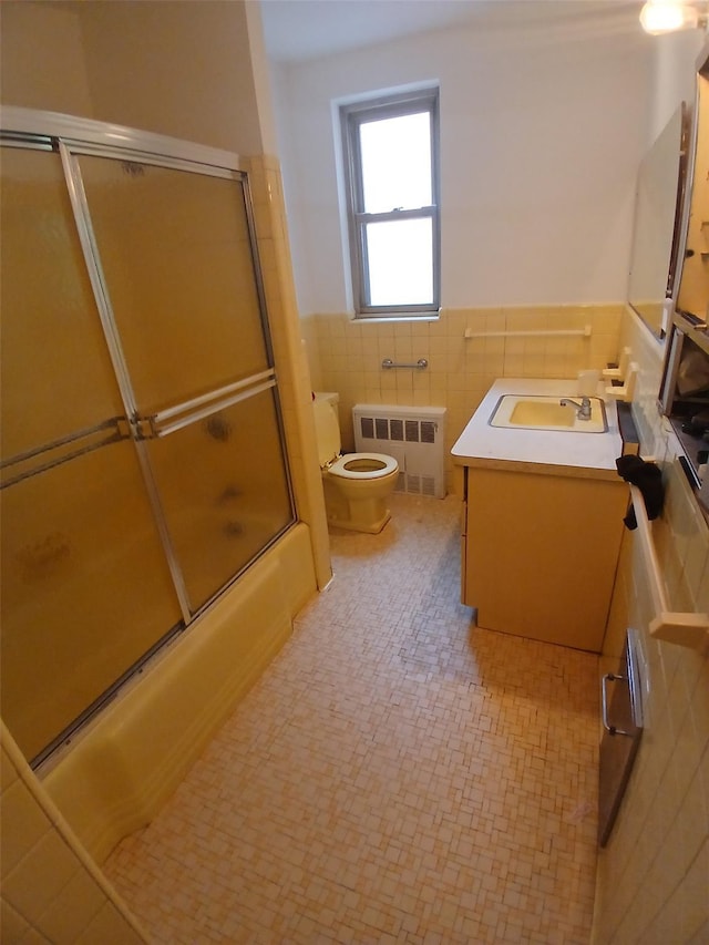 72 Pondfield Rd W Unit 2F, Bronxville, NY 10708 - bathroom featuring radiator heating unit, vanity, tile walls, a wainscoted wall, and bath / shower combo with glass door