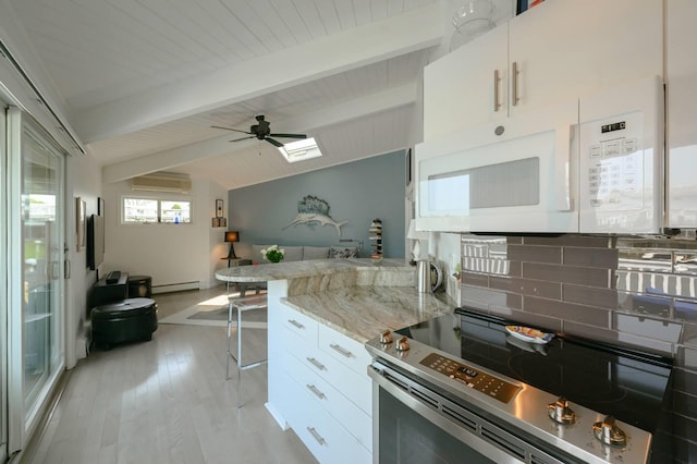 35 Library Ave Unit 8X, Westhampton Beach, NY 11978 - kitchen with stainless steel electric range oven, white microwave, a baseboard radiator, tasteful backsplash, and white cabinetry