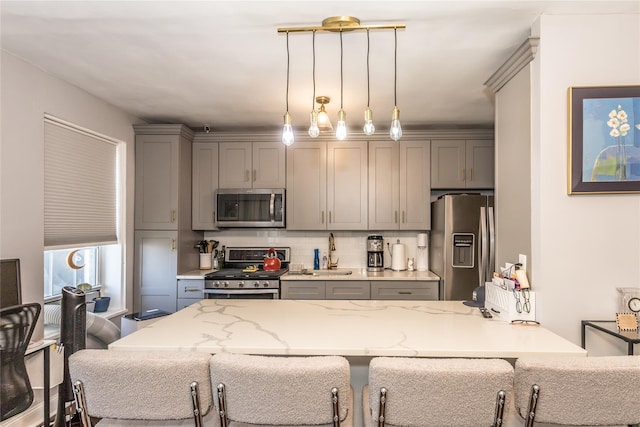 30-47 Hobart St Unit 6, Woodside, NY 11377 - kitchen featuring gray cabinets, stainless steel appliances, tasteful backsplash, a kitchen breakfast bar, and hanging light fixtures