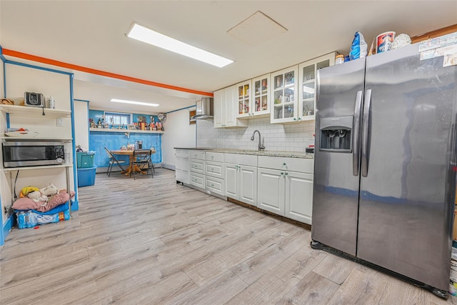 129 Guenther Ave, Valley Stream, NY 11580 - kitchen featuring appliances with stainless steel finishes, wall chimney range hood, light wood finished floors, backsplash, and white cabinets