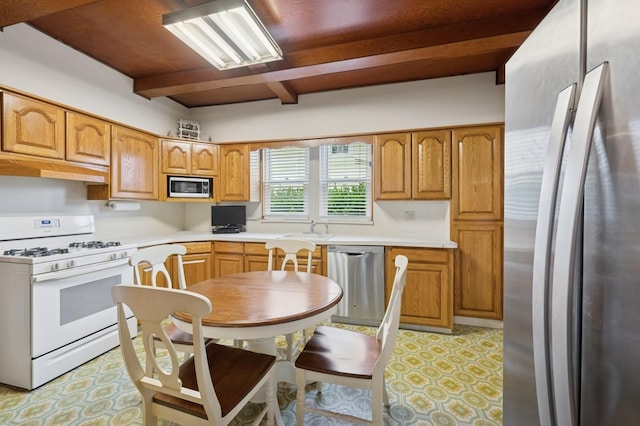45 Crosby Ave, Albertson, NY 11507 - kitchen with appliances with stainless steel finishes, under cabinet range hood, beam ceiling, light countertops, and brown cabinets